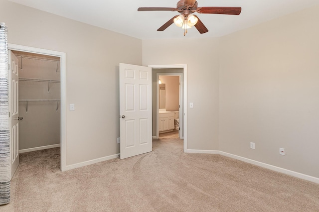 unfurnished bedroom featuring baseboards, a ceiling fan, light colored carpet, a walk in closet, and a closet