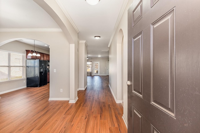 hallway featuring a notable chandelier, crown molding, baseboards, and wood finished floors