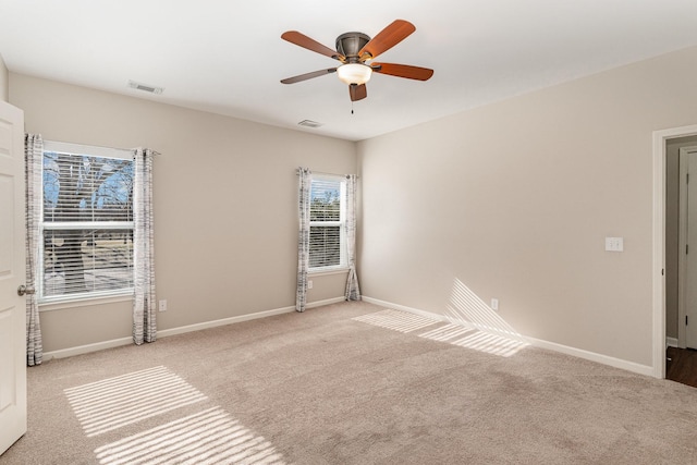 carpeted spare room with a ceiling fan, visible vents, and baseboards