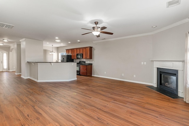 kitchen with visible vents, a fireplace with flush hearth, brown cabinets, open floor plan, and black appliances