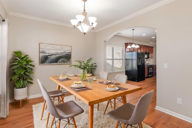 dining space with light wood-style floors, a chandelier, and arched walkways