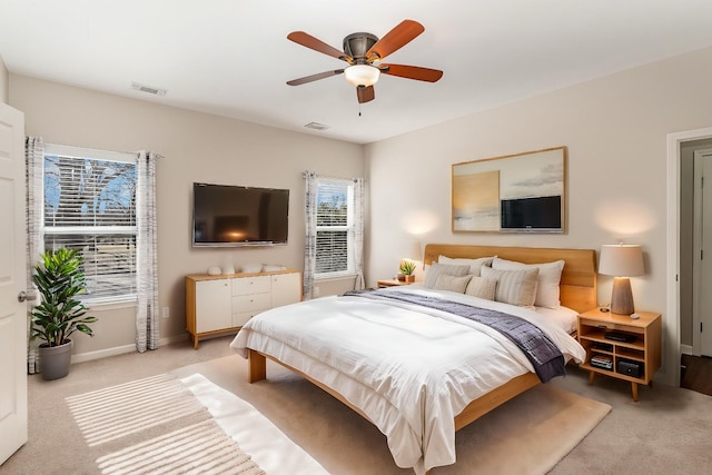 bedroom featuring visible vents, baseboards, a ceiling fan, and light colored carpet