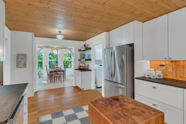 kitchen with freestanding refrigerator, white cabinets, arched walkways, and open shelves