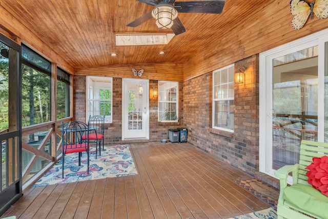 sunroom featuring wooden ceiling, vaulted ceiling with skylight, and ceiling fan