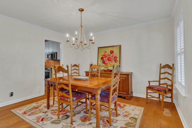 dining area with light wood-style floors, baseboards, ornamental molding, and a chandelier