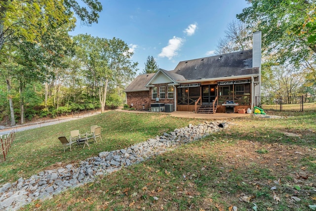 rear view of house featuring fence, a sunroom, a yard, a chimney, and a patio area