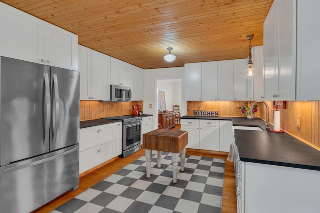 kitchen featuring dark floors, appliances with stainless steel finishes, dark countertops, and a sink