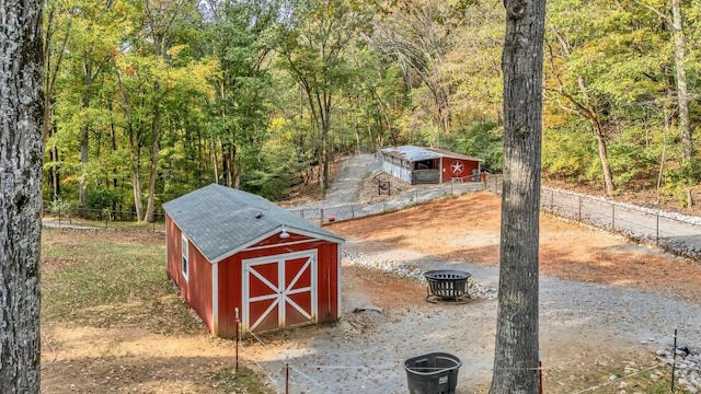 view of shed with fence and a forest view