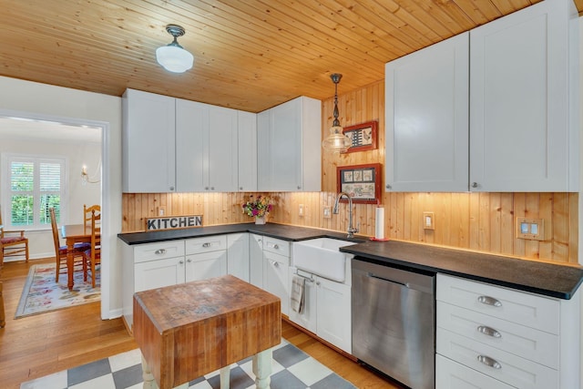 kitchen with dark countertops, white cabinetry, dishwasher, and a sink