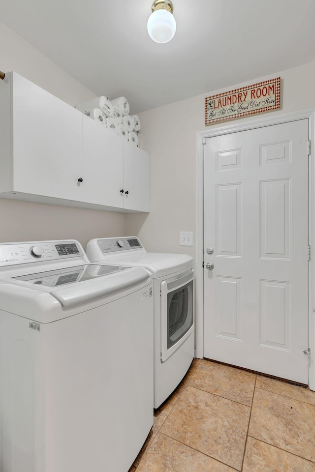 clothes washing area featuring cabinet space and washer and clothes dryer