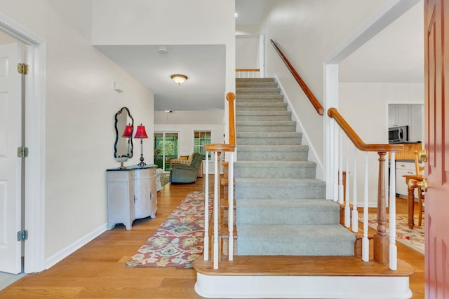 staircase featuring ornamental molding, wood finished floors, and baseboards