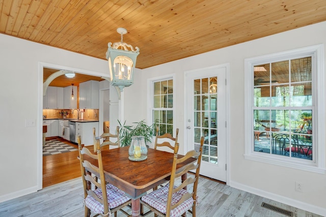 dining room featuring arched walkways, light wood-style flooring, a notable chandelier, wood ceiling, and visible vents