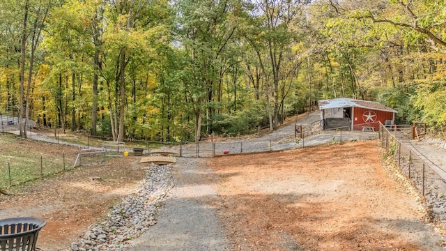 view of yard with an outbuilding, fence, and a forest view