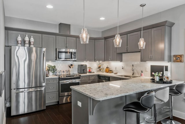 kitchen featuring gray cabinets, appliances with stainless steel finishes, dark wood-type flooring, a sink, and a peninsula