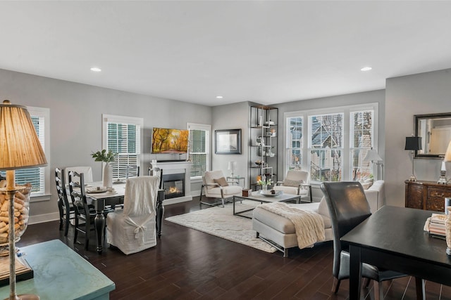 living room with recessed lighting, baseboards, dark wood-type flooring, and a glass covered fireplace