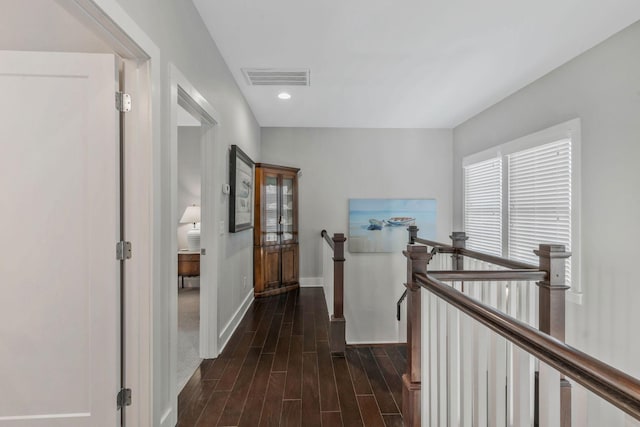 hallway featuring dark wood-style floors, recessed lighting, visible vents, an upstairs landing, and baseboards