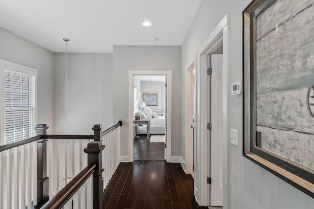 hall with dark wood-type flooring, recessed lighting, an upstairs landing, and baseboards