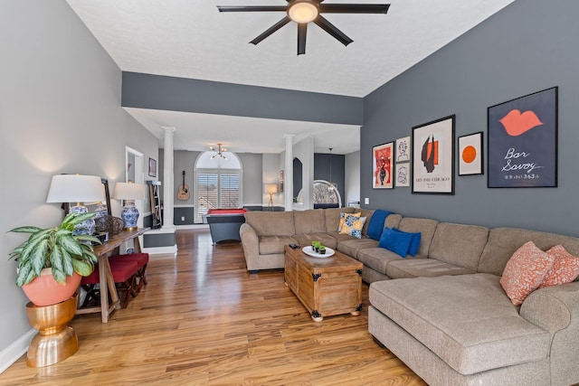 living area with baseboards, decorative columns, a ceiling fan, and wood finished floors