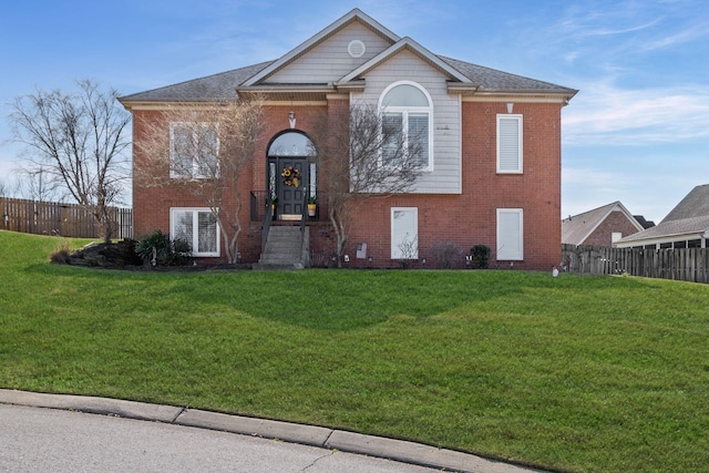 view of front of property with brick siding, a front lawn, and fence