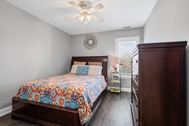 bedroom featuring dark wood finished floors, visible vents, ceiling fan, a textured ceiling, and baseboards