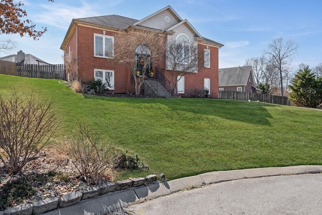 view of front of house featuring fence, a front lawn, and brick siding