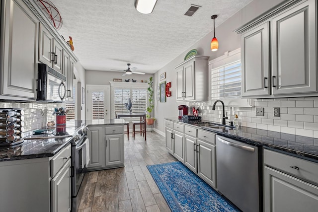 kitchen with stainless steel appliances, a sink, dark wood finished floors, and gray cabinetry