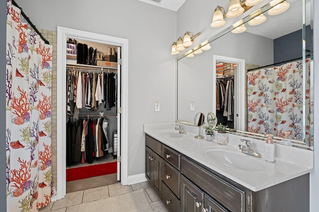 full bathroom with a sink, a spacious closet, baseboards, and double vanity