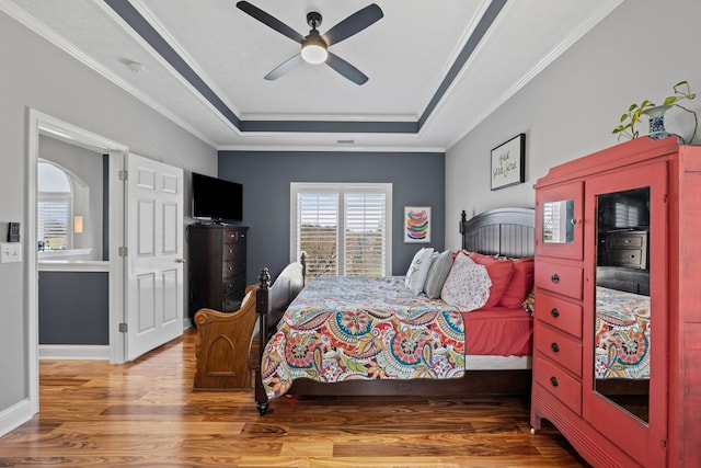 bedroom featuring ornamental molding, wood finished floors, a raised ceiling, and baseboards