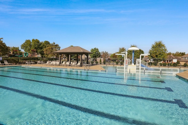 pool with fence, a water play area, and a gazebo