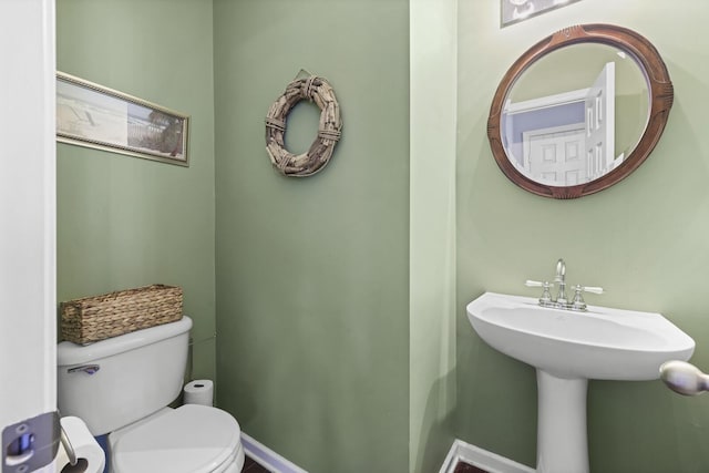 bathroom with toilet, baseboards, and a sink