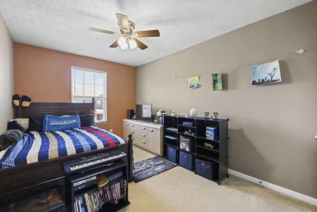 bedroom featuring a ceiling fan, baseboards, a textured ceiling, and light colored carpet