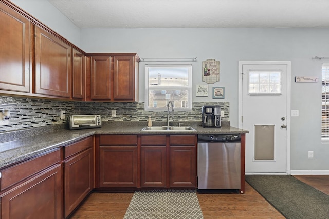 kitchen with tasteful backsplash, dark countertops, dishwasher, and a sink