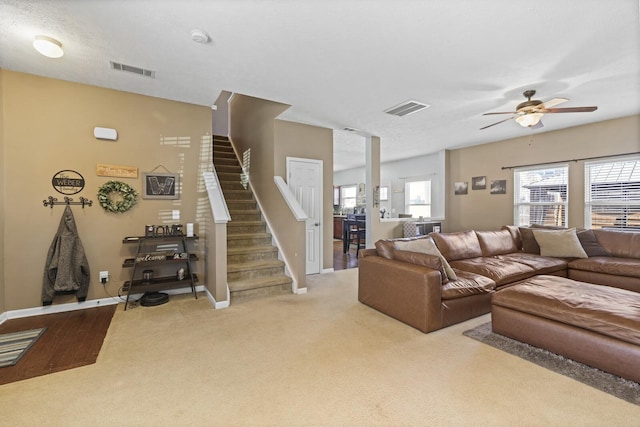 living room with stairway, carpet, visible vents, and ceiling fan