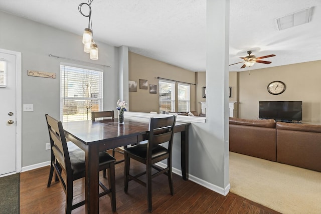 dining space featuring visible vents, dark wood-type flooring, ceiling fan, a textured ceiling, and baseboards