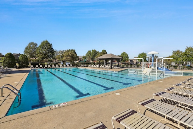 community pool featuring a gazebo, a water slide, a patio area, and a water play area