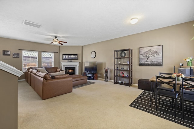 carpeted living area featuring visible vents, a fireplace, baseboards, and ceiling fan