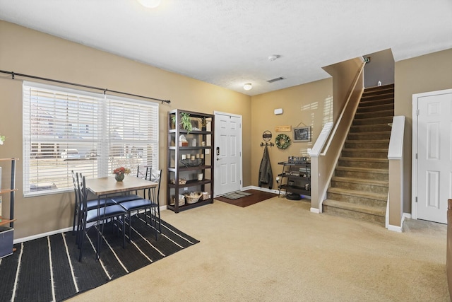 carpeted dining space featuring baseboards and stairs