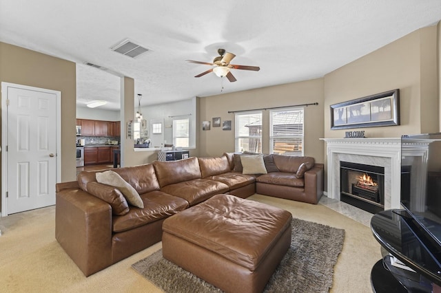 living area featuring visible vents, a fireplace, light carpet, and ceiling fan