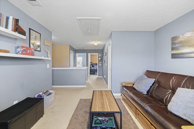 living area with attic access, visible vents, baseboards, a textured ceiling, and carpet floors