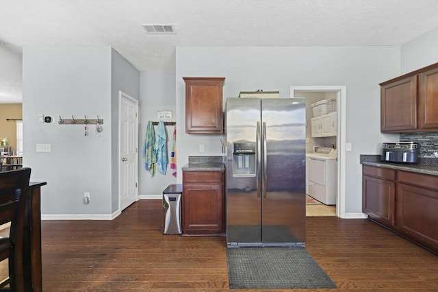 kitchen featuring stainless steel fridge, visible vents, decorative backsplash, dark countertops, and dark wood-type flooring