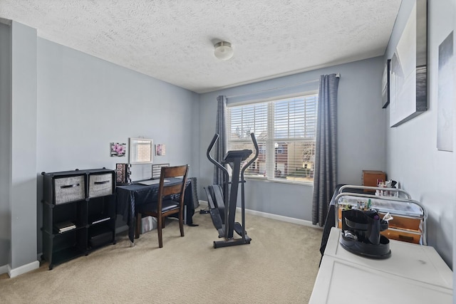 workout area with light colored carpet, a textured ceiling, and baseboards