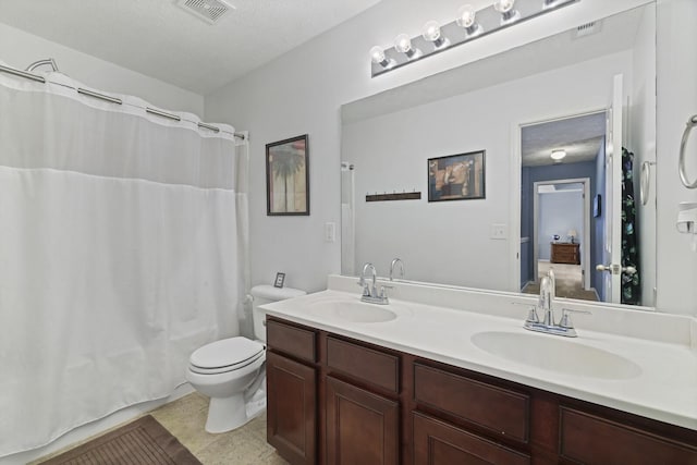 bathroom with toilet, double vanity, a sink, and visible vents