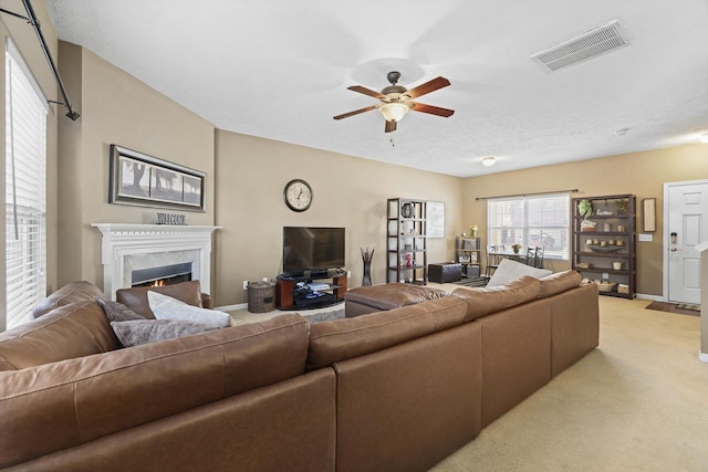 living room with visible vents, a ceiling fan, a high end fireplace, light carpet, and baseboards