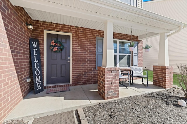 entrance to property with a porch and brick siding