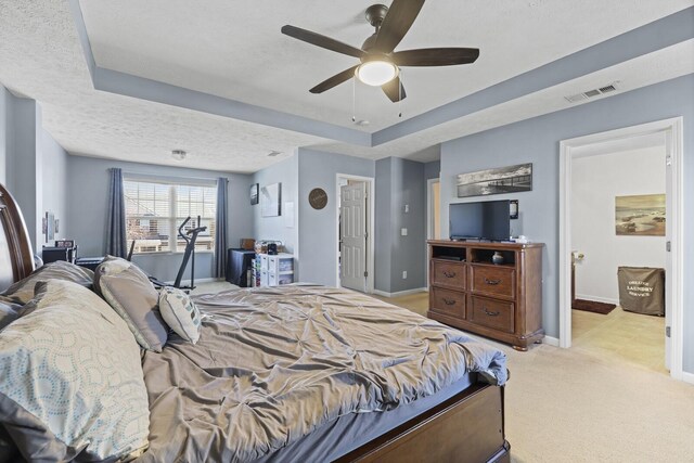 bedroom with light carpet, baseboards, visible vents, a tray ceiling, and a textured ceiling