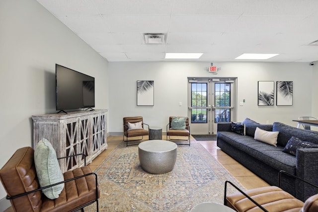 tiled living room with a paneled ceiling, french doors, and visible vents