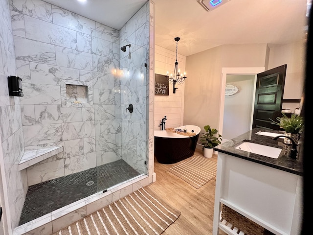 full bathroom with wood finished floors, a sink, a soaking tub, a shower stall, and double vanity