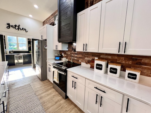 kitchen with beverage cooler, range with electric cooktop, white cabinetry, freestanding refrigerator, and light wood finished floors