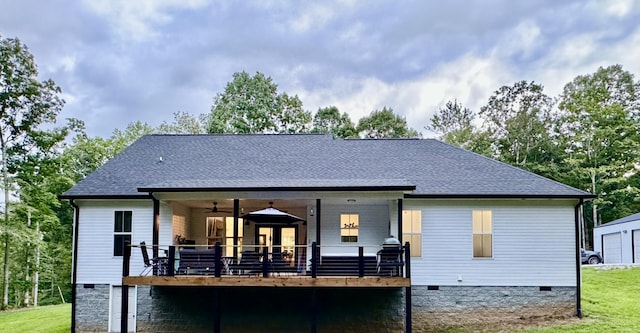 rear view of house featuring roof with shingles, crawl space, and a lawn