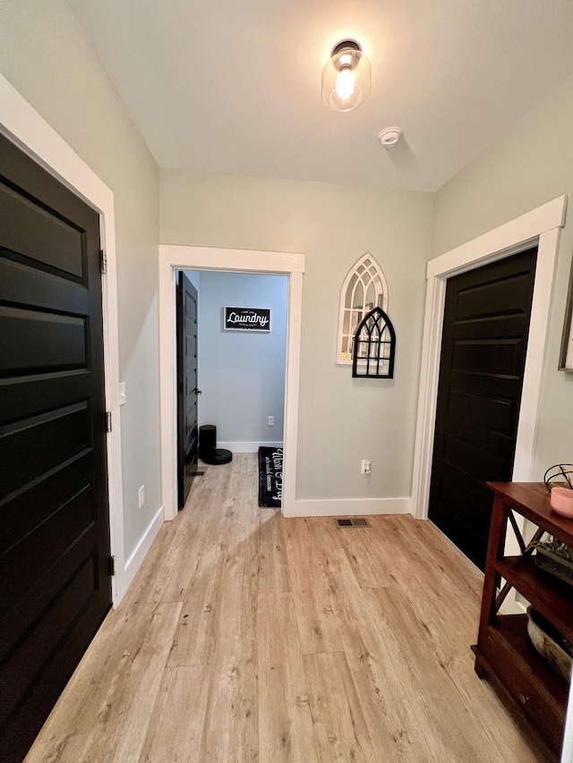 hallway featuring light wood-style floors, visible vents, and baseboards